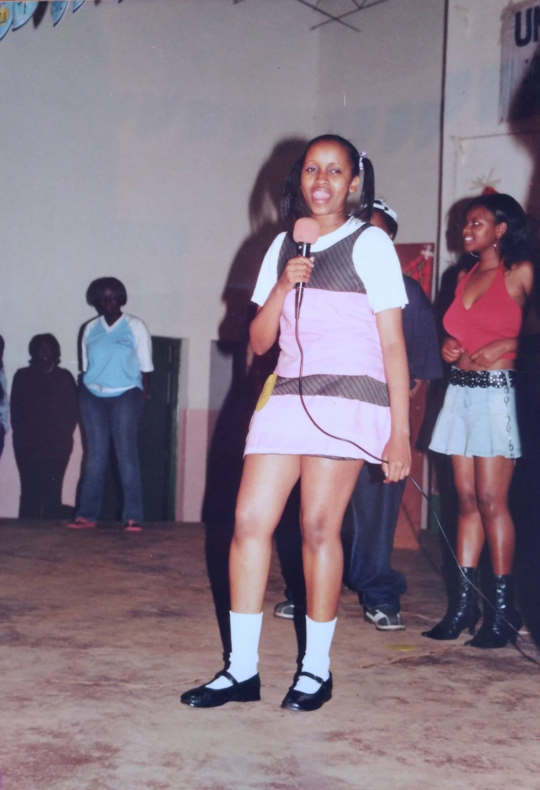 A student modelling a pink-and-grey pinafore dress on stage at the school pageant.